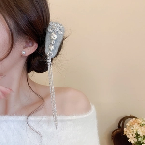 Macro detail of grey velvet hair clip with sparkling rhinestones and long fringe tassels
