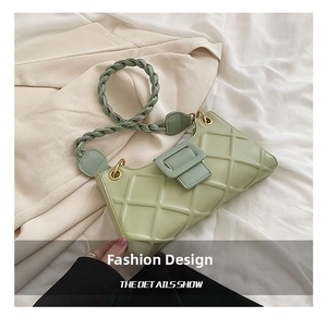 Detail view of the quilted texture and braided handle on the light green baguette bag