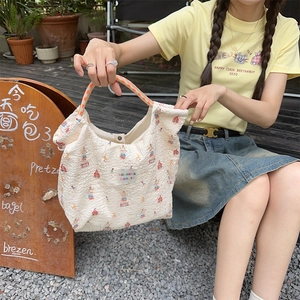 Detail of cream popcorn texture tote bag with circus print and orange checkered handles
