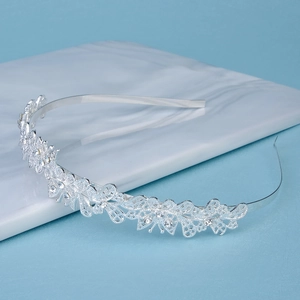 Close-up of silver hollowed pattern headband with rhinestones on a blue background