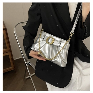Détail du sac plissé argenté avec boucle dorée et bandoulière en chaîne élégante