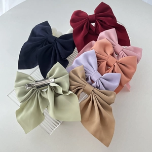 Detail of colorful bow hair clips with metal duckbill grips on a wavy display