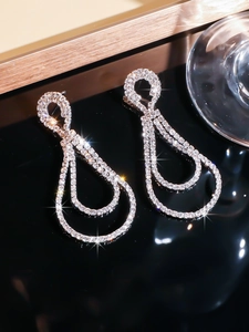 Detailed close-up of double-layer teardrop rhinestone earrings with brilliant silver finish
