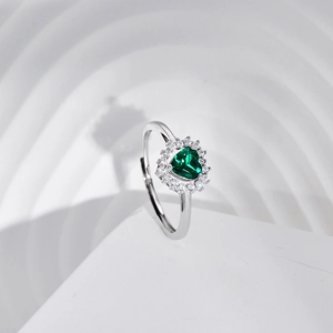 Macro shot of silver ring with heart-cut green emerald and diamond halo setting