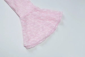 Détail rapproché des manches évasées en dentelle rose d'une robe ajustée courte