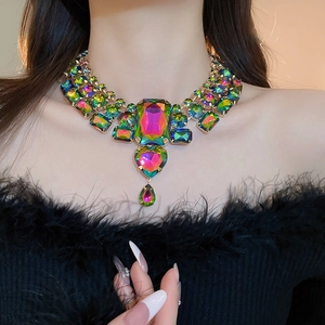 Macro shot of iridescent heart and teardrop crystal pendant on gold statement necklace
