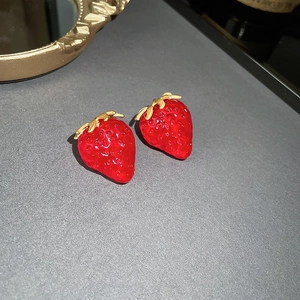 Charmante rote Erdbeer-Ohrstecker mit goldenen Blättern auf mattgrauer Fläche