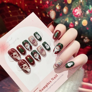 Detailed view of Christmas press-on nails with reindeer and Santa Claus art on cards