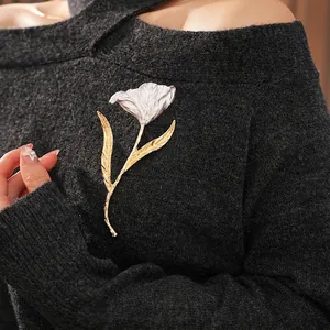 Elegant white and gold tulip brooch with textured petals pinned on a grey knit sweater