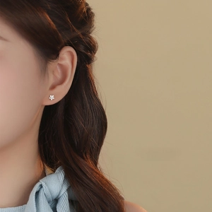 Elegant S999 sterling silver flower stud earrings worn by a model in a minimalist style