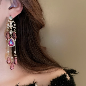 Macro detail of long crystal tassel earrings with purple stones and pearls on model