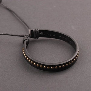 Men's punk black leather bracelet featuring bronze metal studs on a dark background