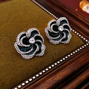 Detailed macro view of black flower earrings with sparkling crystals on velvet padding