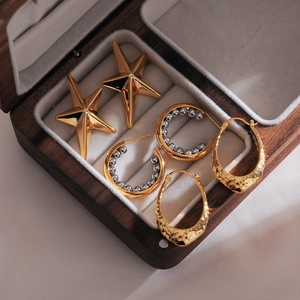 Three pairs of elegant gold star and textured hoop earrings in a dark wood jewelry box