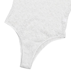 Close-up of white floral lace bodysuit detail showing intricate texture and fabric edge