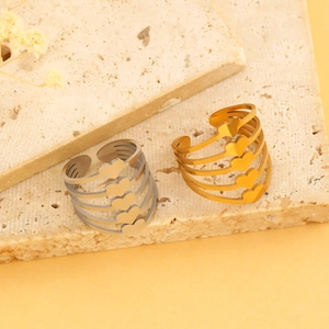 Detail of multi-layer heart shaped open rings in gold and silver finish on stone