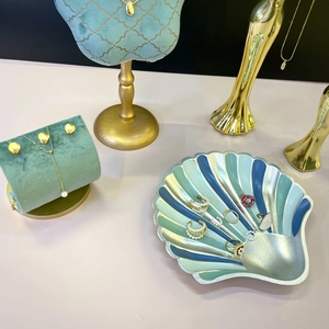 Golden jewelry display stand with velvet bust and shell tray for necklace storage