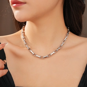 Close-up of silver geometric chain necklace showing adjustable link texture on collarbone