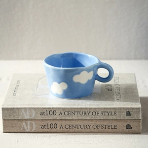 Detailed view of a blue ceramic cloud mug placed on books for a cozy morning vibe