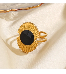 Vue macro d'une bague dorée vintage avec centre en émail noir et détails soleil texturés