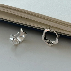 Close-up of minimalist S925 sterling silver geometric wave earrings on a notebook