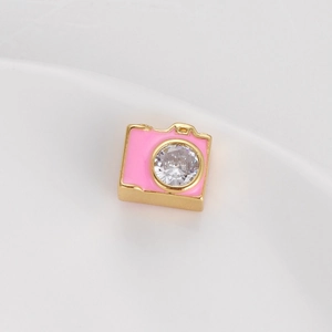 Vista macro di una perla a forma di fotocamera dorata con smalto rosa e zircone lucente