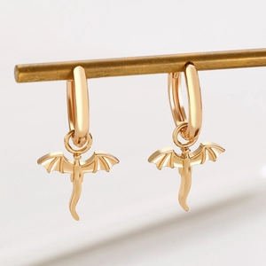 Golden dragon-shaped hoop earrings with diamond accents hanging on a display stand