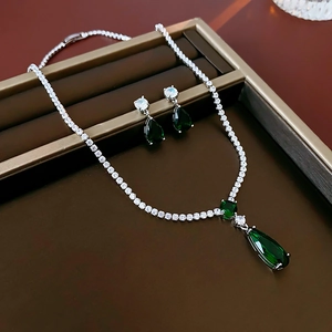 Detailed view of silver jewelry set with emerald drop pendants and zirconia accents