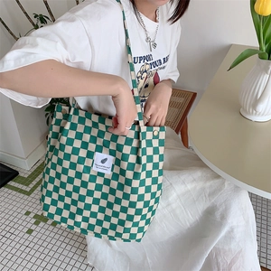 Detail view of corduroy tote bag with green and beige checkerboard pattern and snap button