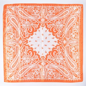 Flat lay detail of a large orange square satin scarf with white paisley patterns