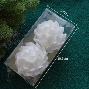 Close-up of two white glitter petal Christmas ornaments in a clear display box
