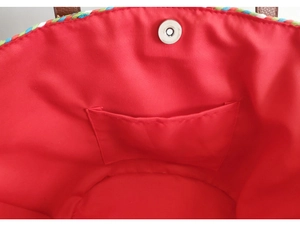 Close-up of woven bag interior with red fabric lining, inner pocket and silver magnetic clasp