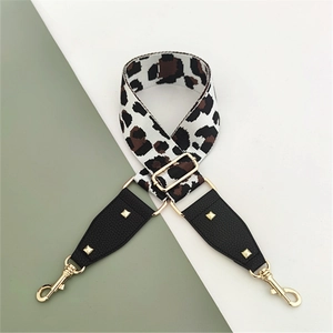 Macro shot of leopard print bag strap with gold lobster clasps and black leather accents