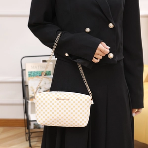 White crossbody chain bag with yellow print and gold strap on black outfit
