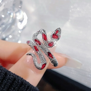 Macro shot of a silver snake ring with red gemstone accents on a finger