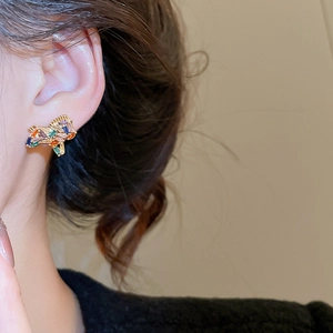Detail of multi-color gemstone horse earring worn by a model in warm lighting