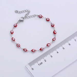 Detailed close-up of a red Evil Eye bracelet with silver chain and measuring ruler