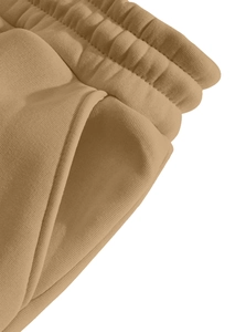 Detail of khaki jogger pants showing elastic waistband, side pockets and cotton texture