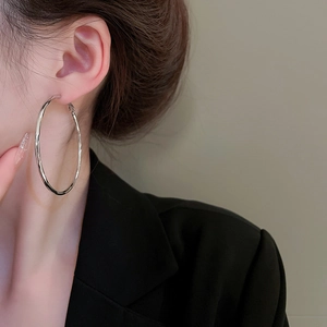 Polished silver hollow hoop earring shown on model in a minimalist fashion style