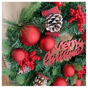 Detail eines Weihnachtskranzes mit roten Beeren, Zapfen und Merry Christmas Schild