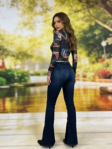 Dettaglio di jeans svasati blu scuro slim fit abbinati a un top a maniche lunghe con stampa