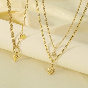 Detail of layered gold stainless steel necklaces with heart and star pendants on silk