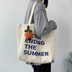 Detail of minimalist canvas tote bag with blue summer text and orange persimmon charm