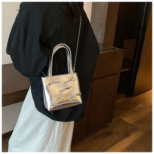 Model view of silver metallic handbag featuring bow accents and elegant chain strap