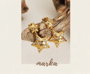 Macro detail of gold star earrings with cubic zirconia and wrinkled metal texture