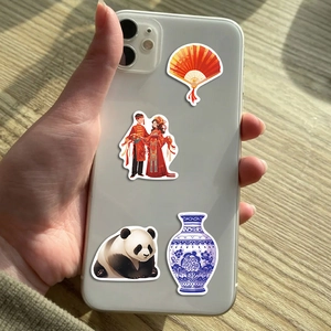 Detail showing traditional Chinese stickers with fans and pandas on a smartphone case