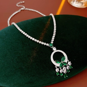 Vue détaillée du pendentif papillon émeraude et gemmes en goutte sur velours vert