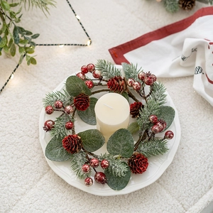 Weihnachtlicher Kerzenring mit roten Beeren und Zapfen auf festlichem Tisch