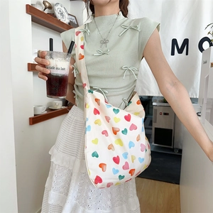 Lifestyle view of a large canvas tote bag with colorful heart patterns worn over the shoulder