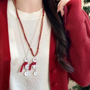 Détail du collier bonhomme de neige de Noël avec chaîne argentée sur tricot rouge